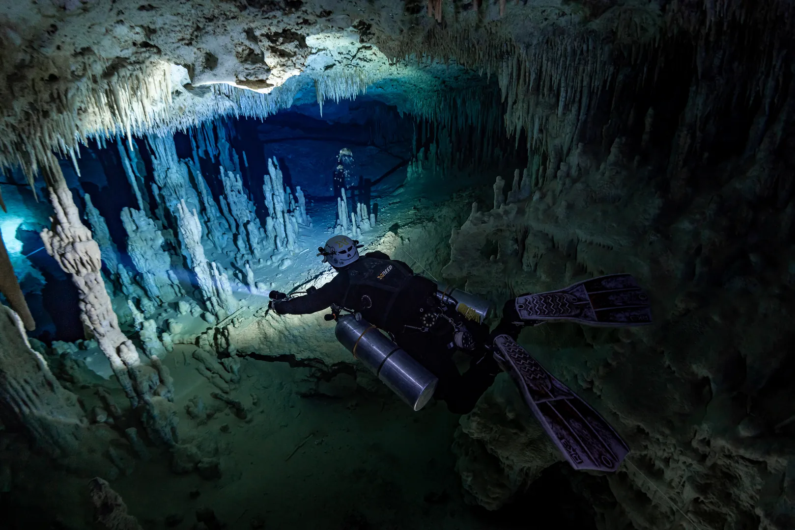 Technical diver exploring a Tulum cave with cinematic blue lighting