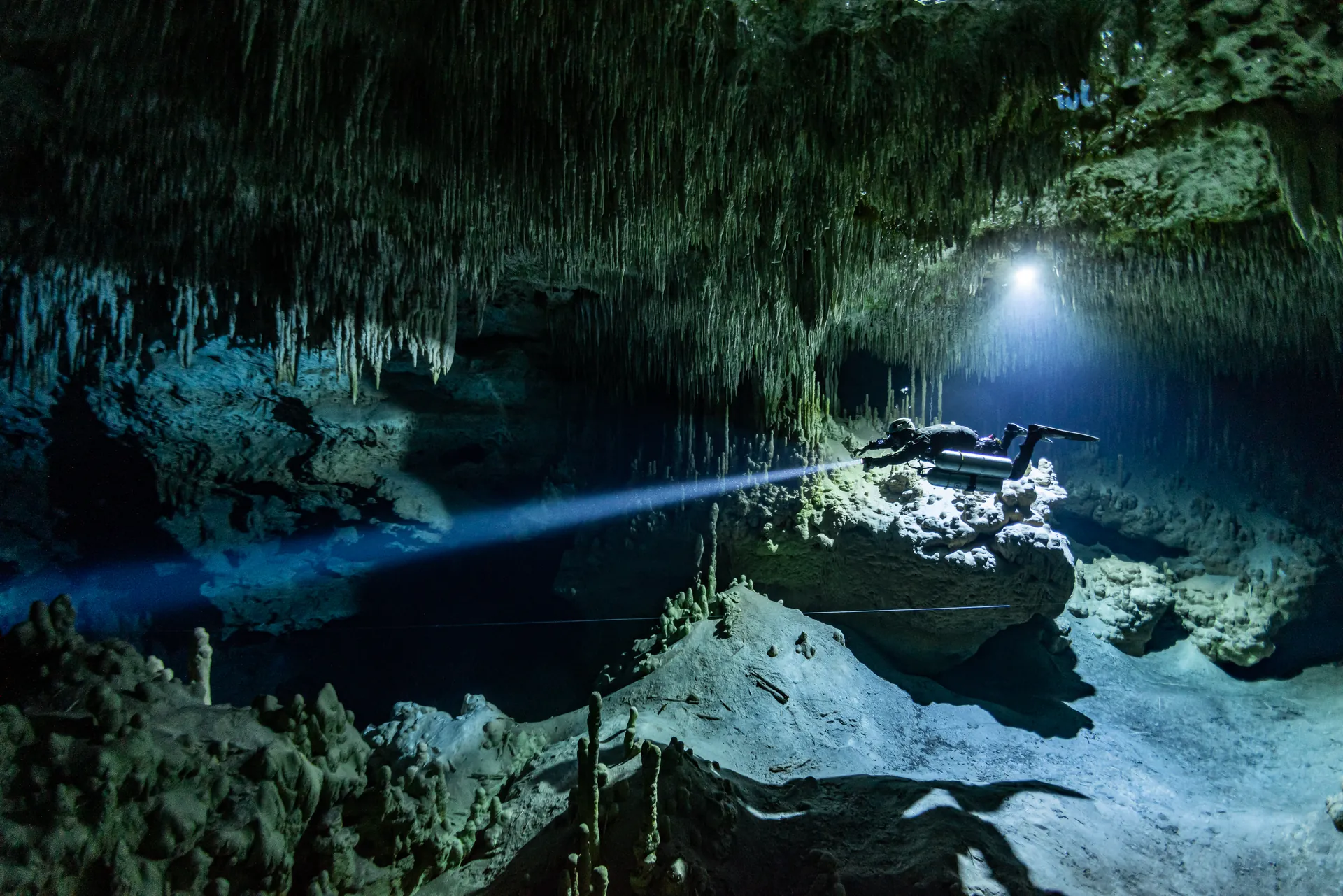 Technical diver with side mount configuration in dark cave environment